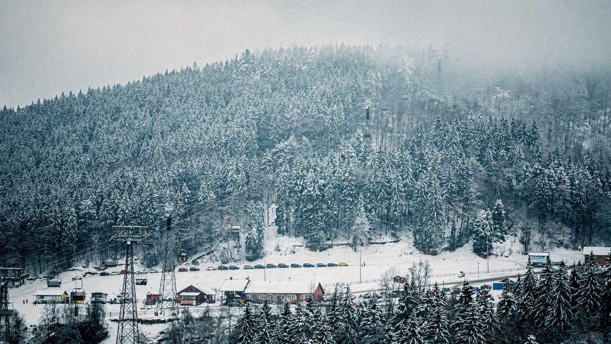 Snow-covered fir ridge above a Carpathian resort base with a chairlift line